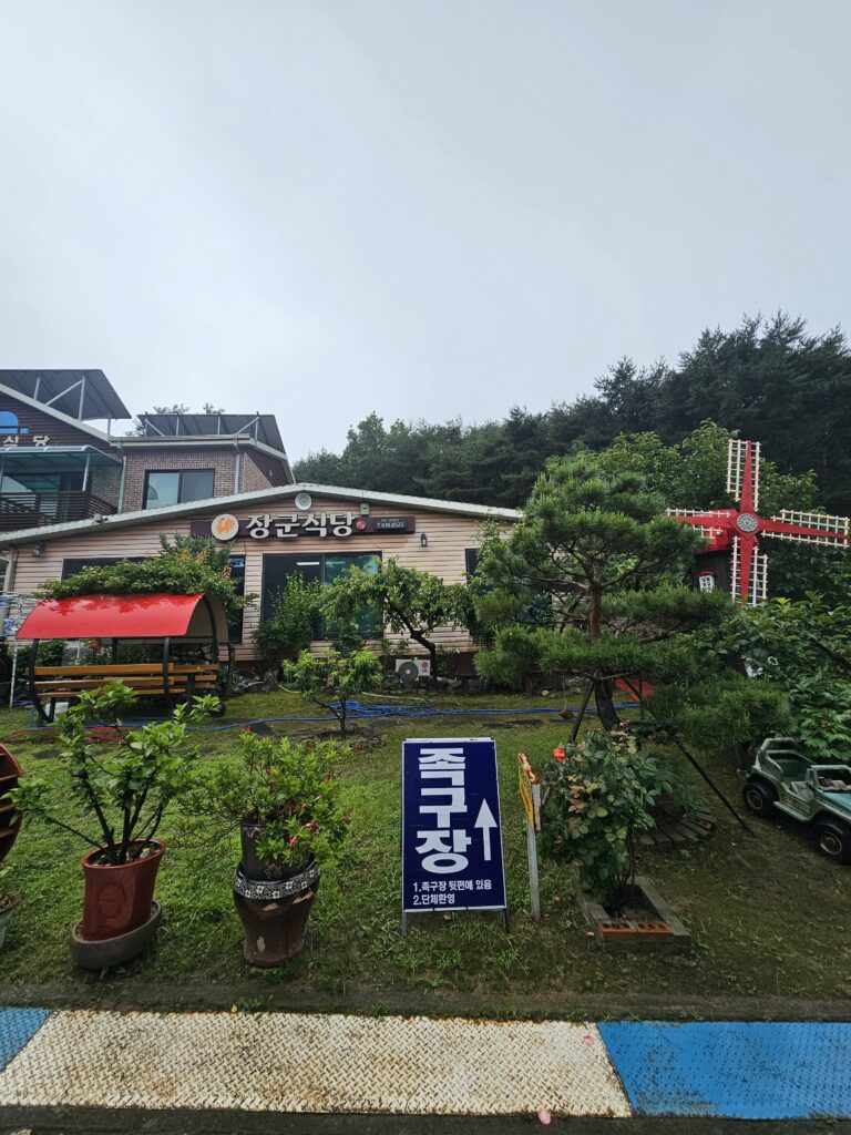 Janggun Sikdang garden and building with a sign pointing to the jokgu court.