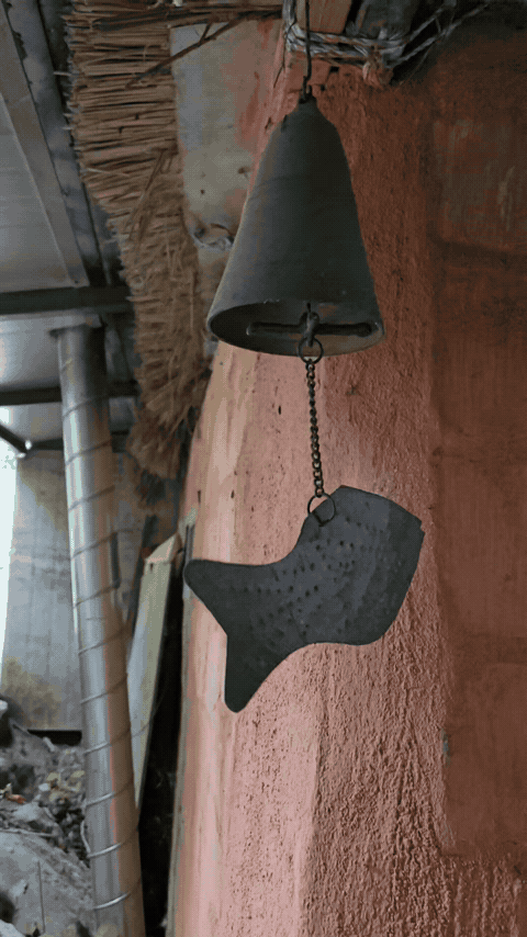 Hanging metal bell with a fish-shaped ornament at Janggun Sikdang.