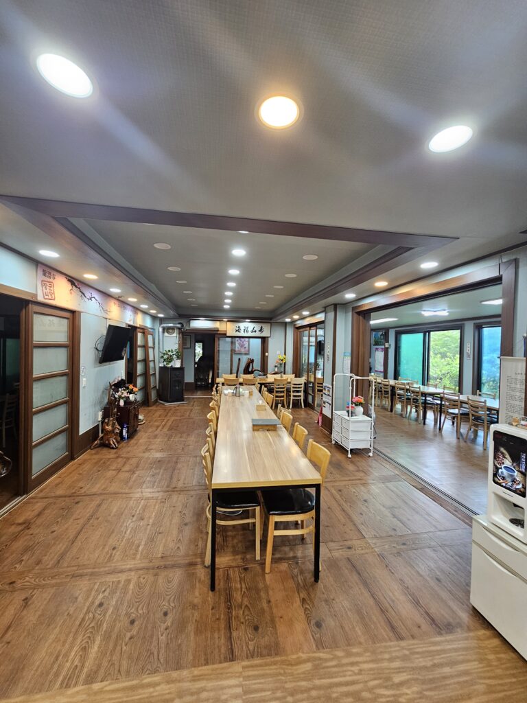 Spacious Janggun Sikdang dining hall with long wooden table and bright ceiling lights.