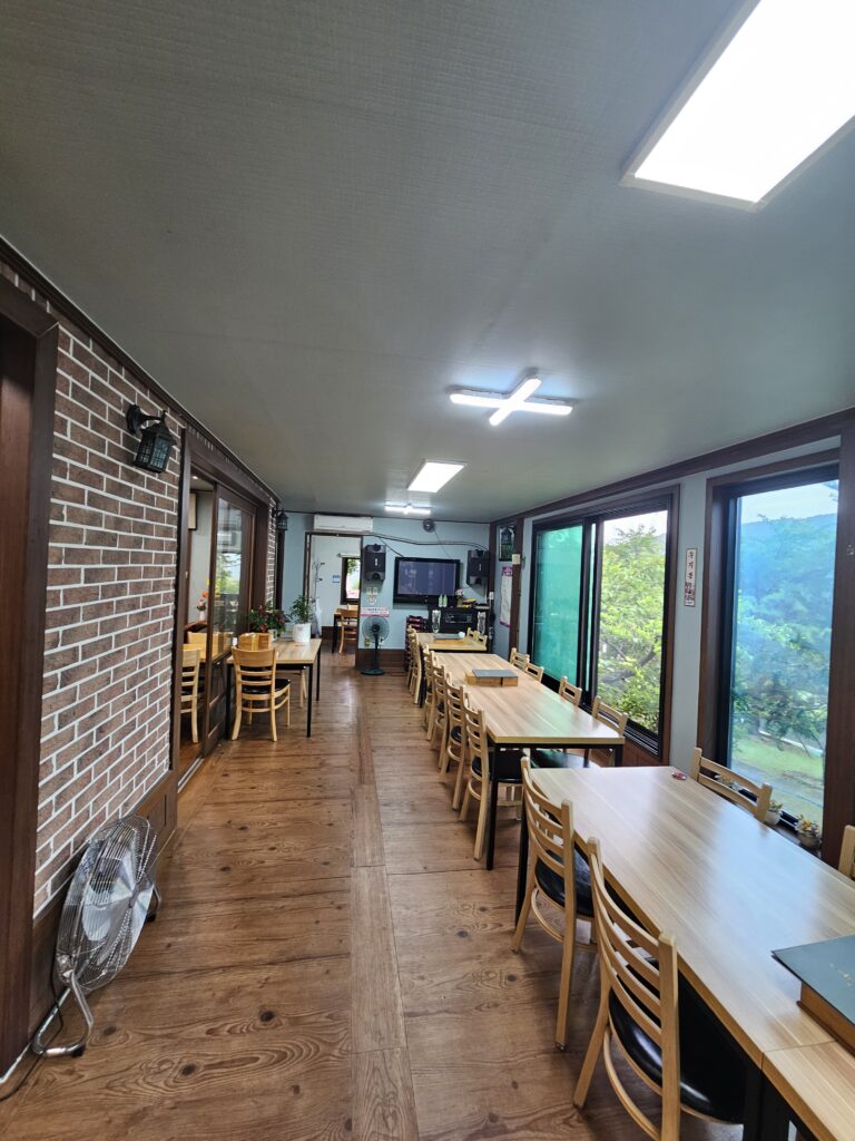 Long tables and chairs beside large windows with screen and audio equipment at the far end.