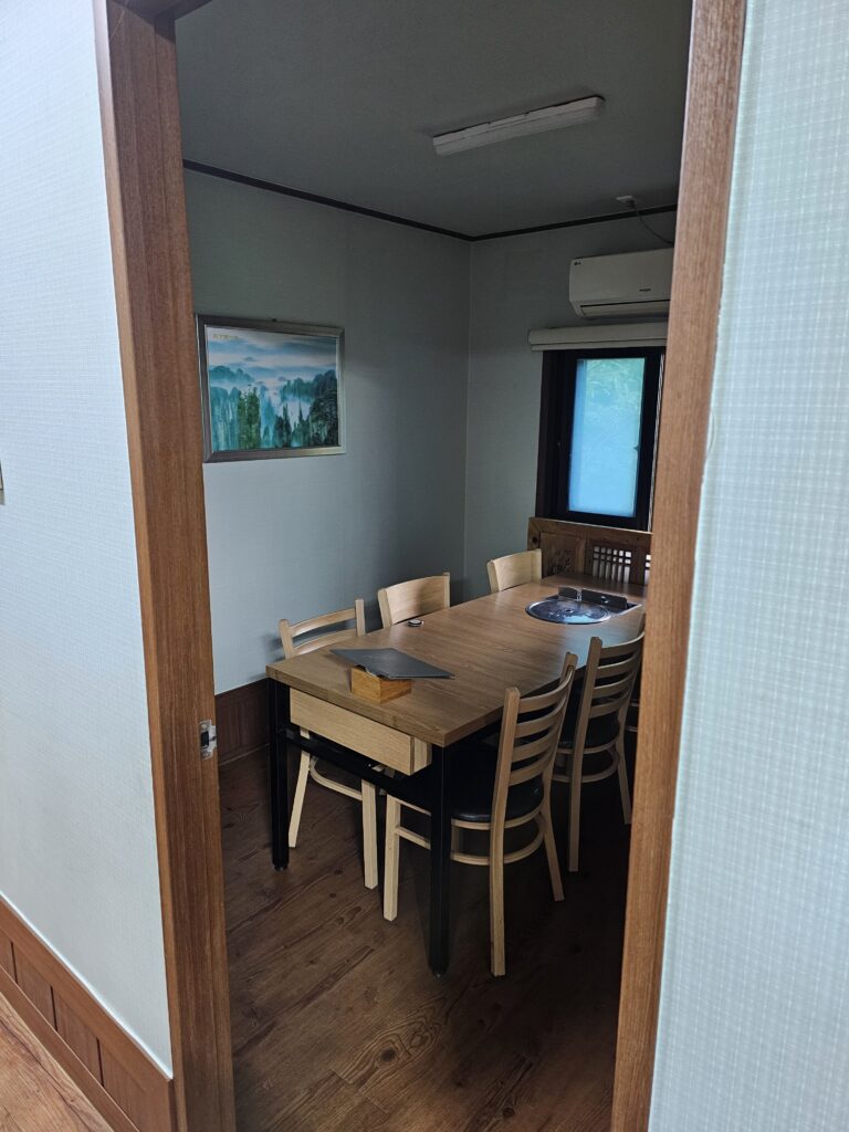 Private dining room at Janggun Sikdang with wooden table, chairs, window, and air conditioner.