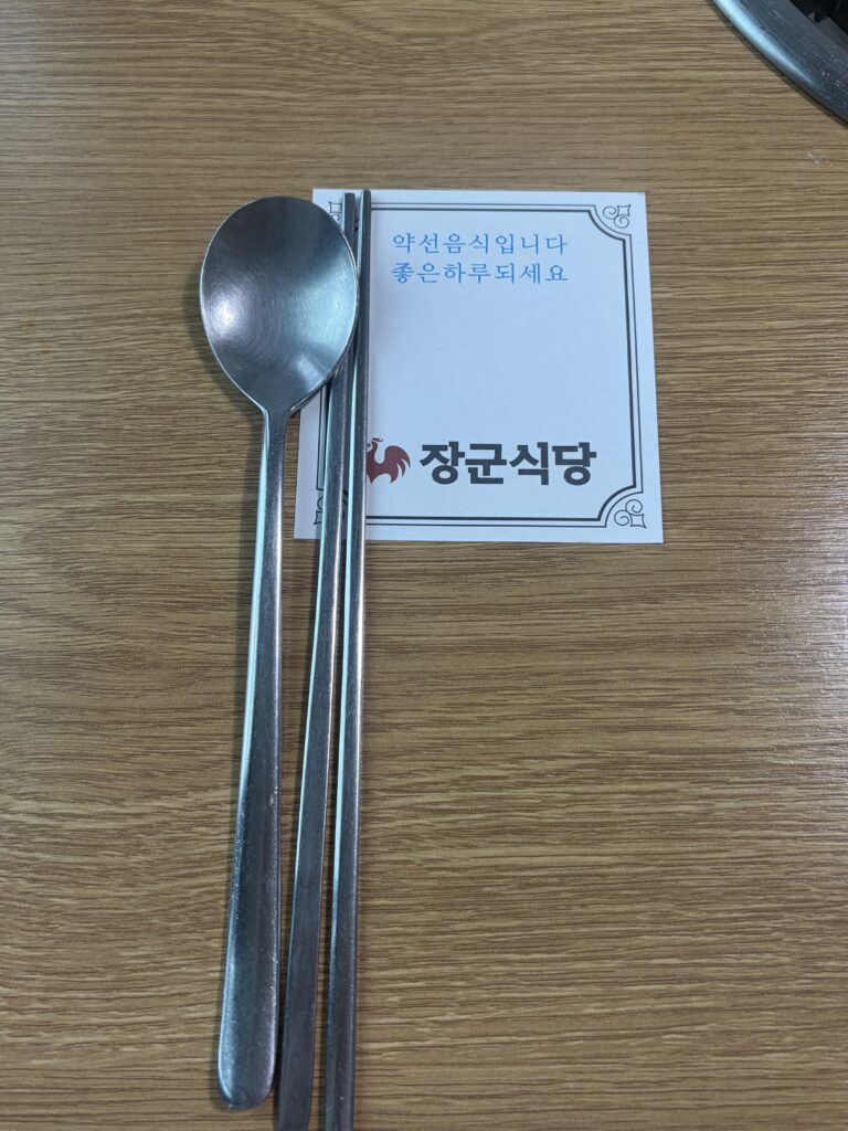 Spoon and chopsticks on paper reading yakseon food and Janggun Sikdang.