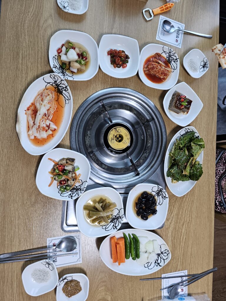 Kimchi, leafy salad, beans, acorn jelly, pickles, vegetables, salt, and dipping paste at Janggun Sikdang.