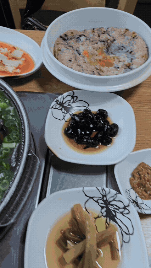 Moving overview of the full Janggun Sikdang meal with banchan, sticky rice, and duck baeksuk.