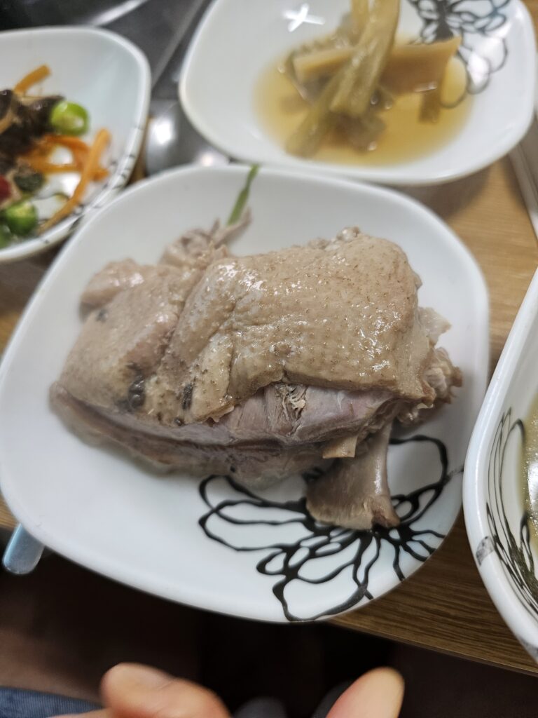 Large bone-in duck piece with skin and glossy broth on a white plate.