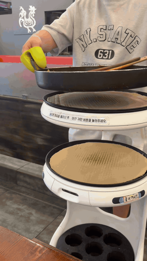 Dakgalbi pan being transferred from serving robot to table in Daegu
