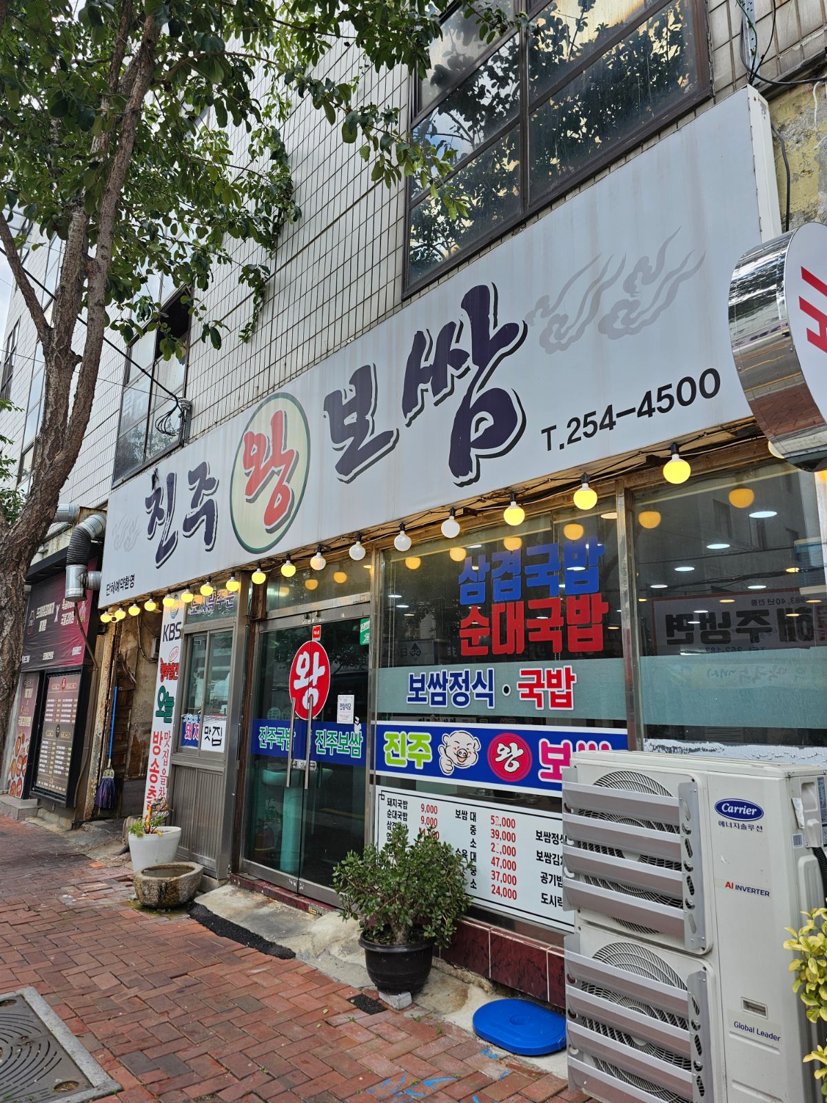 Exterior of Jinju Wang Bossam with large menu signs for bossam set meal and gukbap