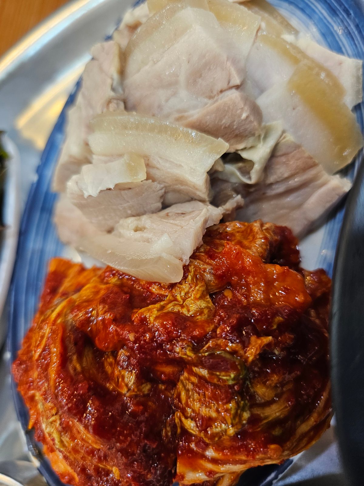 Close view of bossam pork and red bossam kimchi on a plate