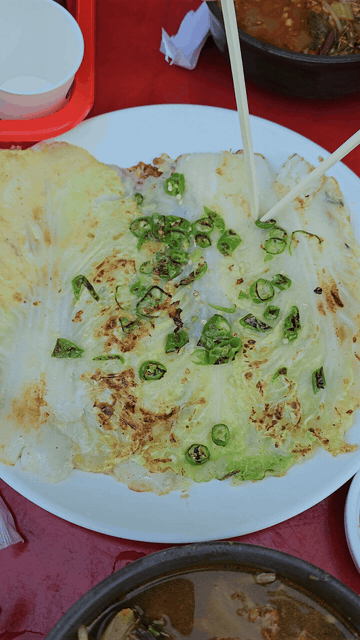 Tearing the Napa cabbage pancake into pieces with chopsticks