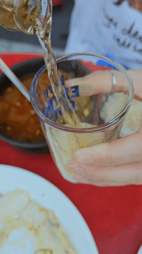 Pouring bottled beer into a glass next to the Napa cabbage pancake
