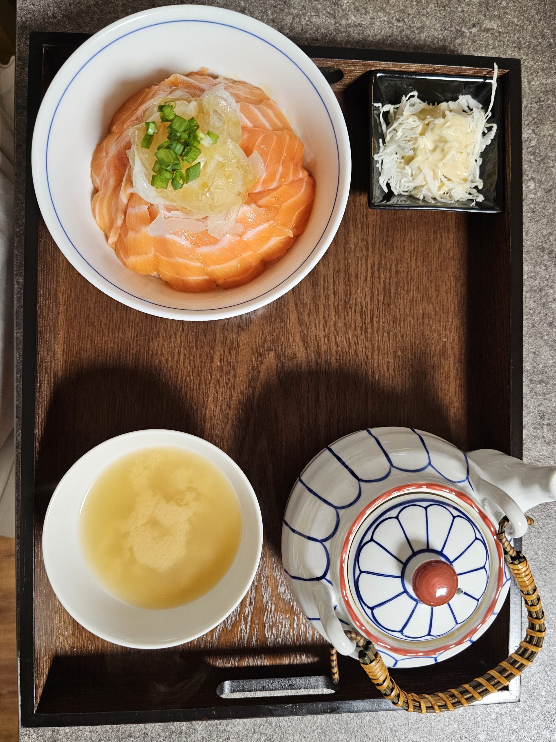 スープ、ドレッシングのかかったキャベツ、お茶漬け用ピッチャーが付いたサーモン丼