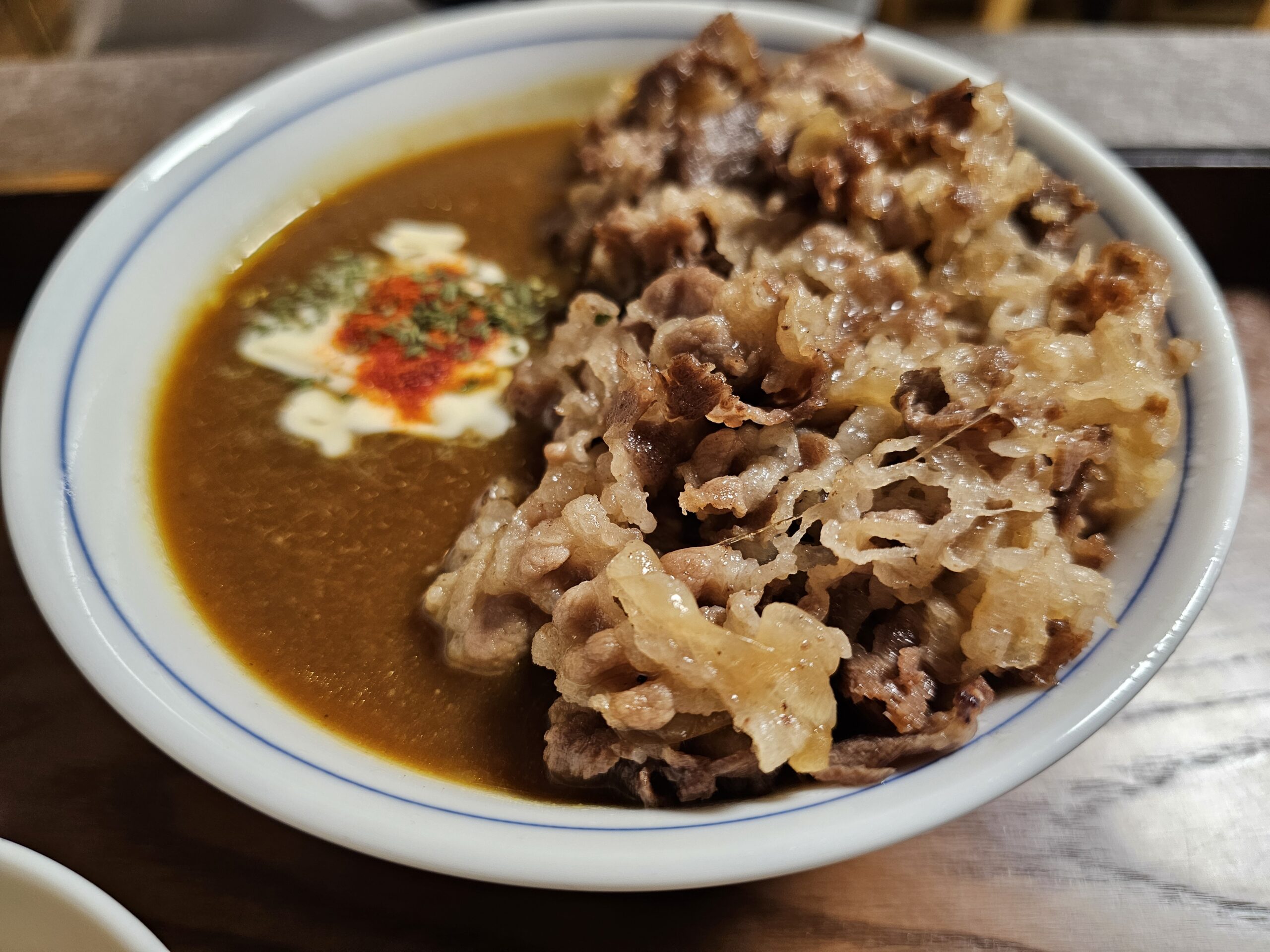 薄切りの牛肉と玉ねぎの横の濃いカレー