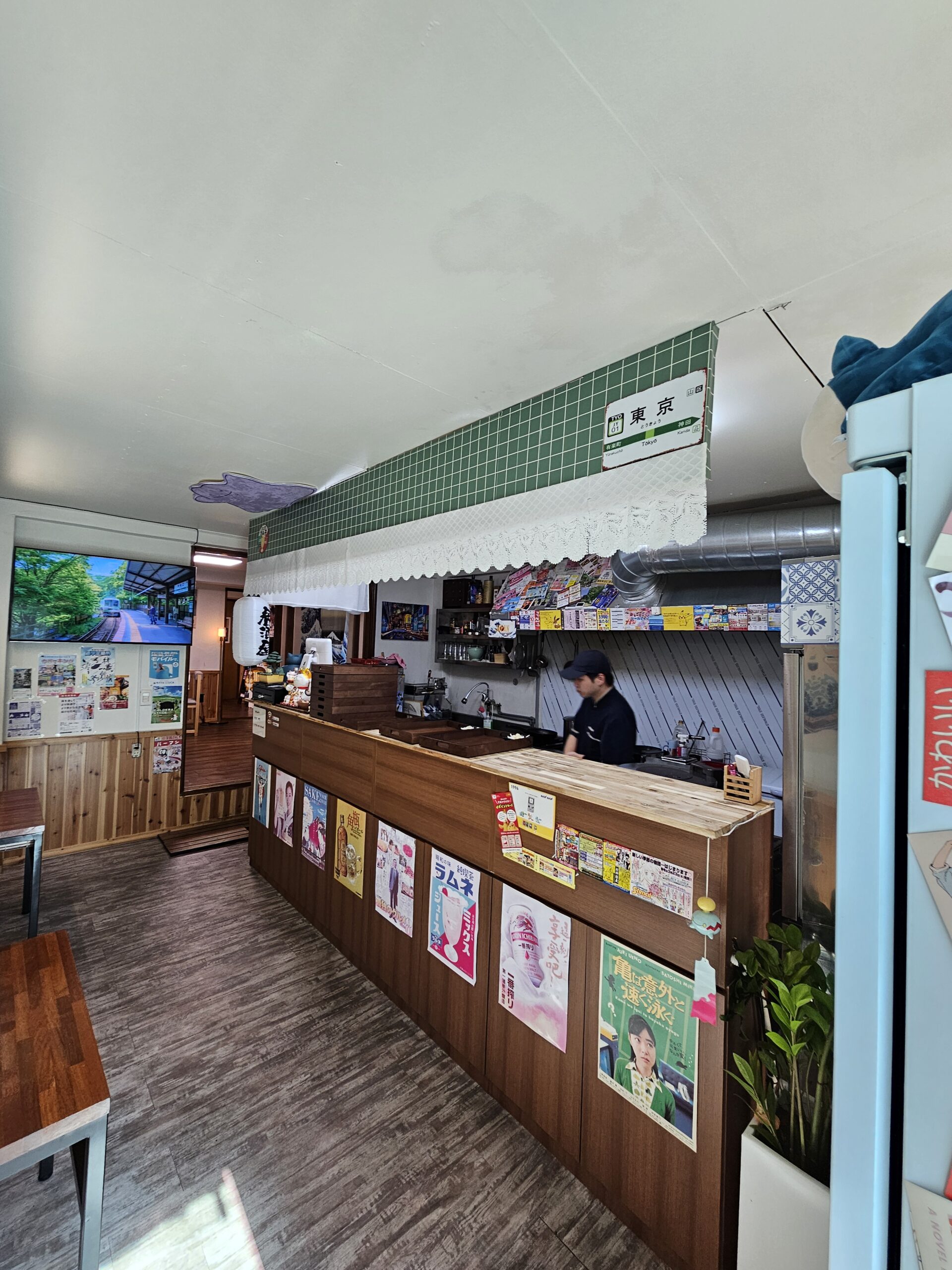 日本のポスターで覆われたカウンターの奥にあるオープンキッチン