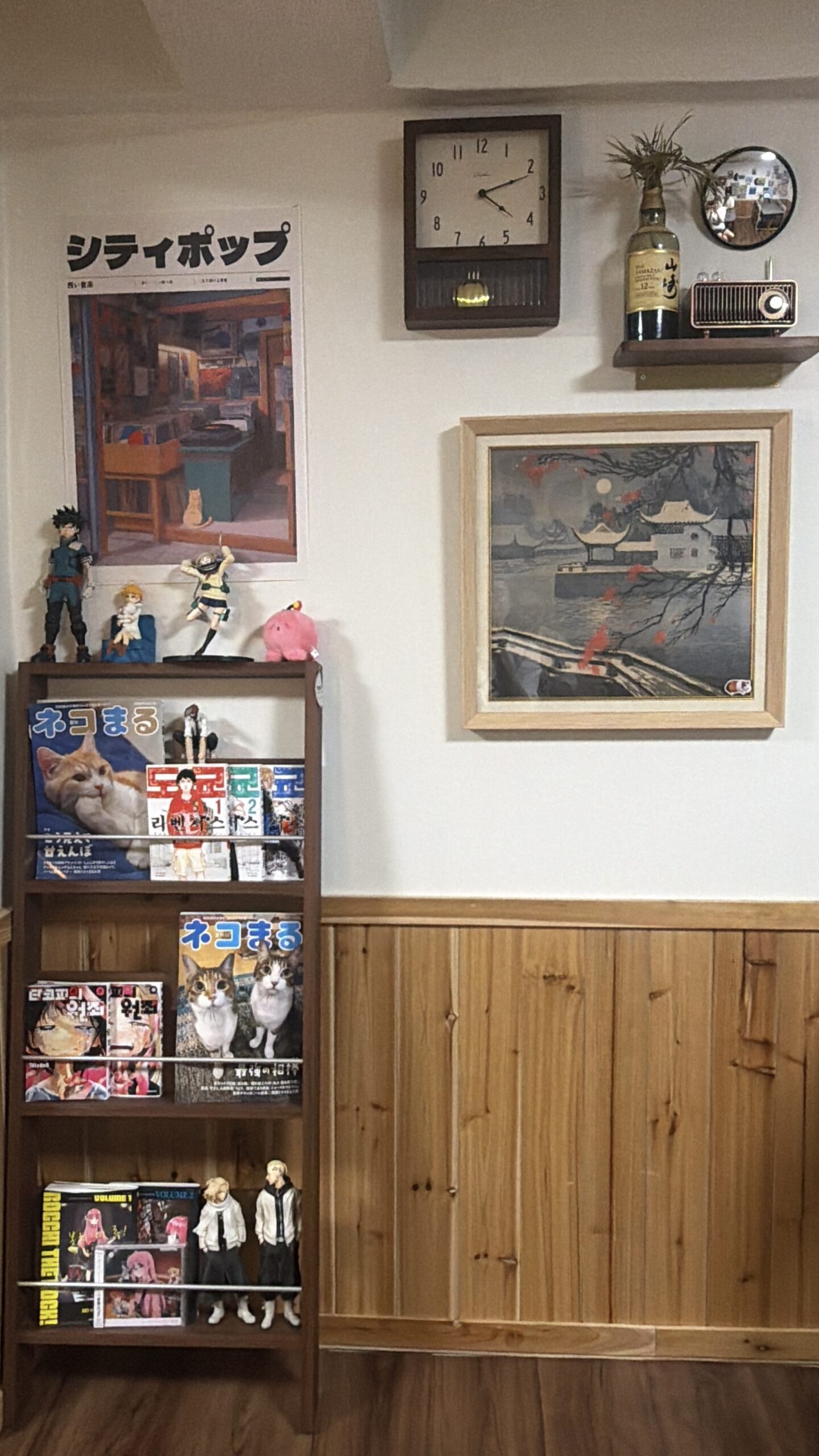 日本のポスター、壁掛け時計、ウイスキーボトル、ラジオ、漫画の本棚