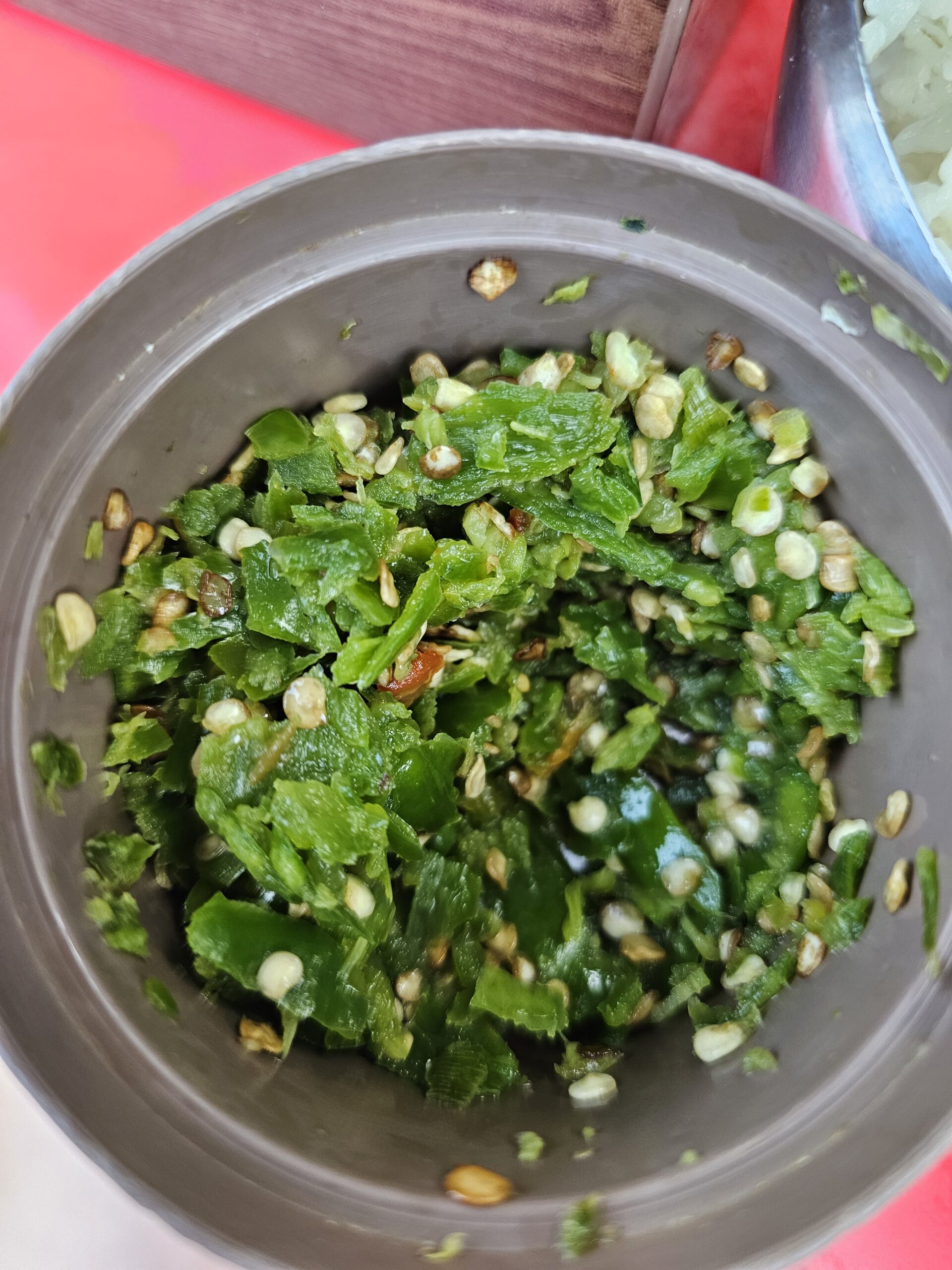 Container of finely chopped green chili with the white seeds left in