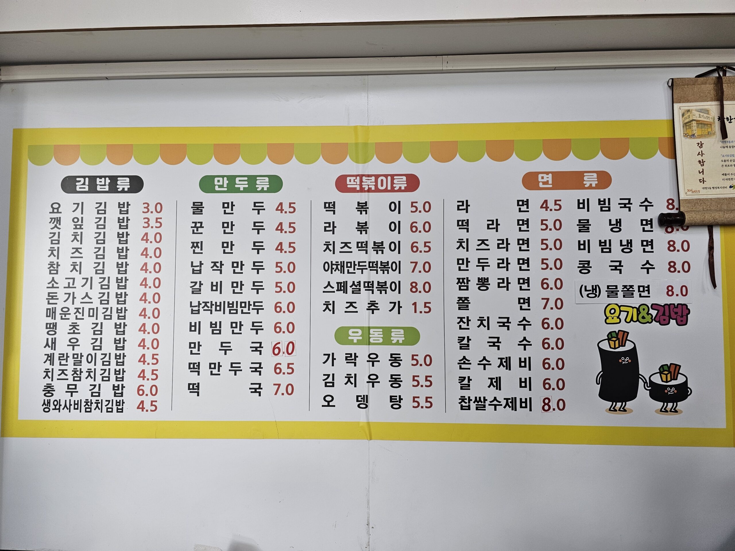 キンパ、餃子、トッポッキ、うどん、麺類に分かれ、価格が書かれたメニューボード