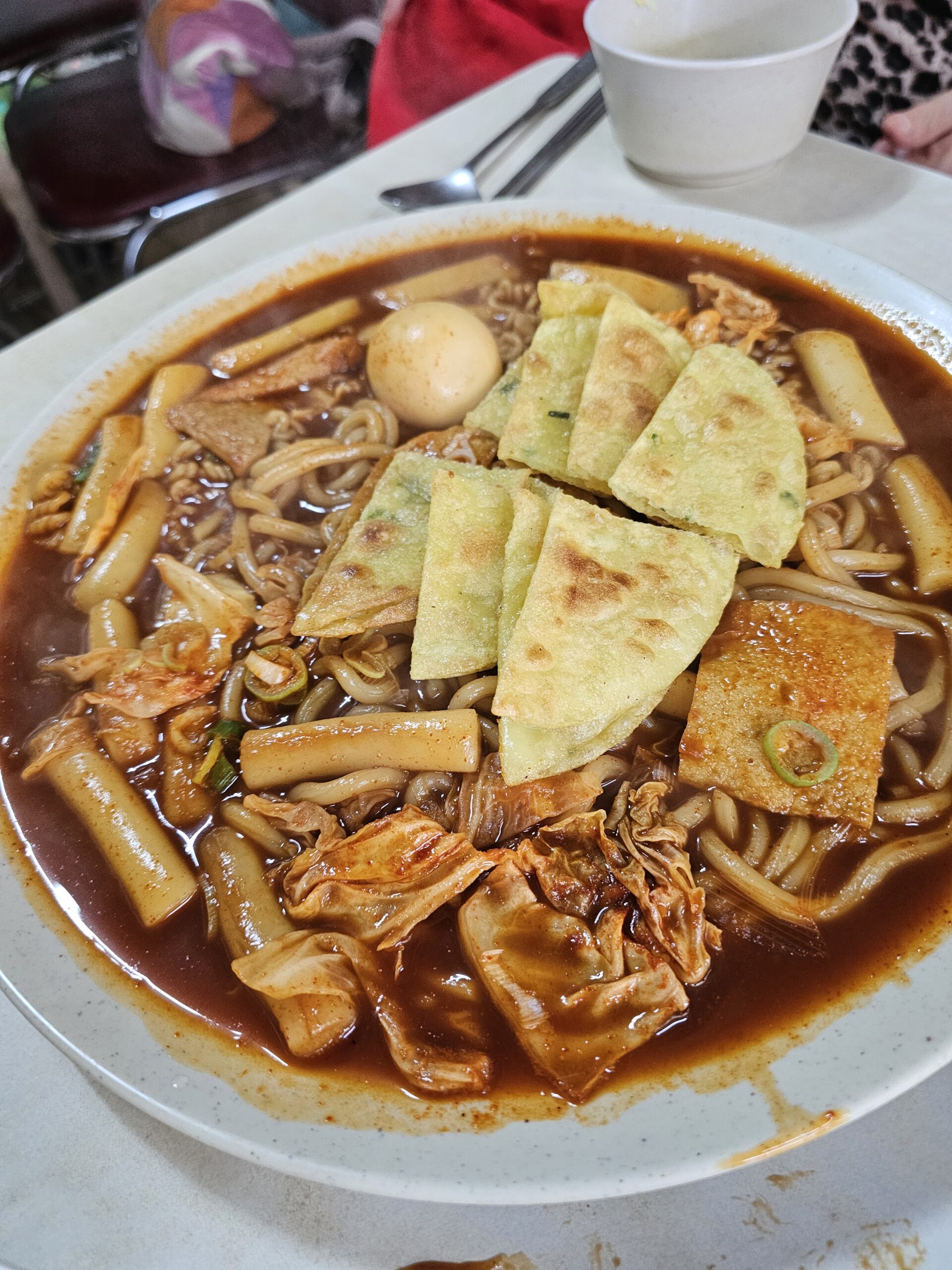 Rice cakes and noodles topped with browned flat dumplings and scallions