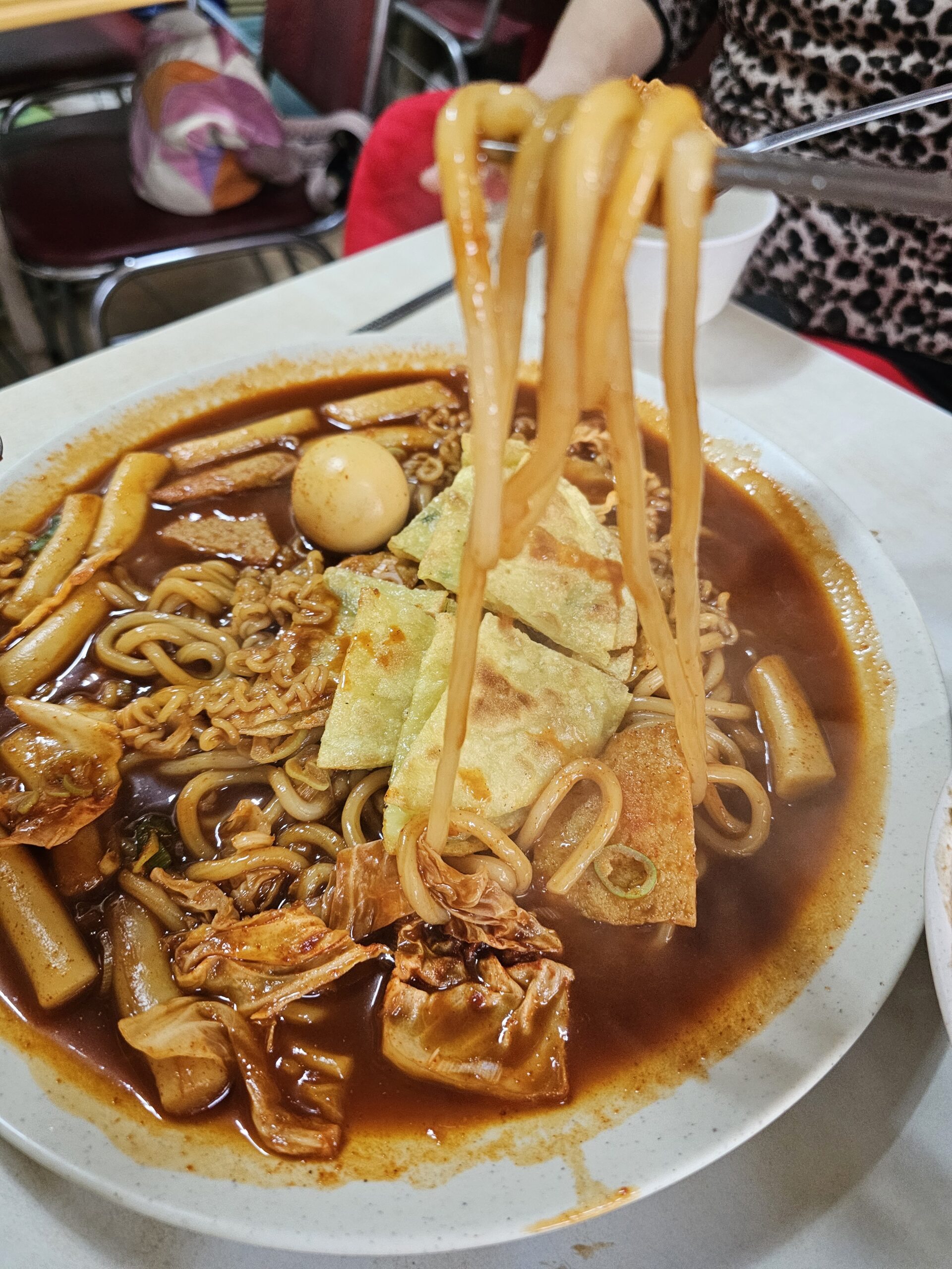 Thick noodles among rice cakes, curly noodles, boiled egg, and fish cake
