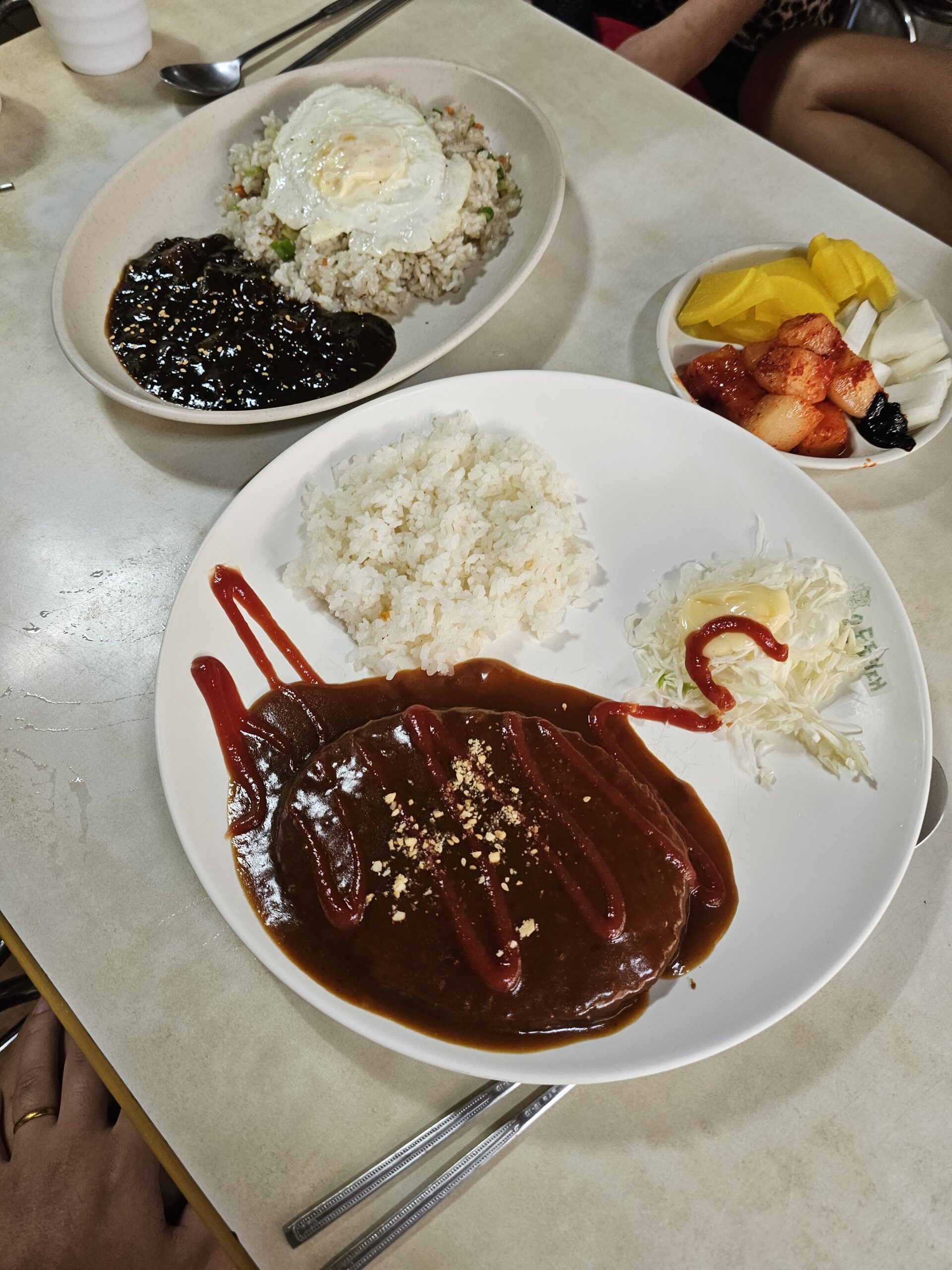 Dongaseu with rice and cabbage salad beside Bokkeumbap topped with a fried egg