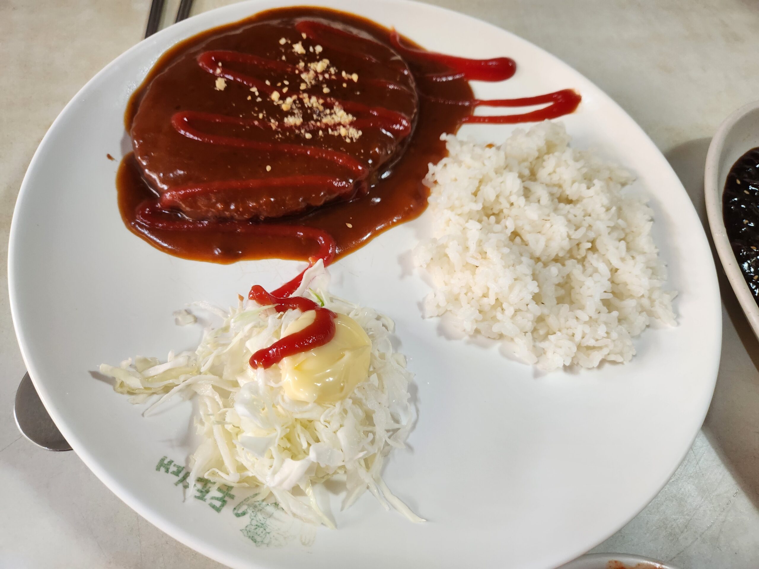 Dongaseu sprinkled with crushed peanuts beside cabbage salad with mayonnaise and ketchup