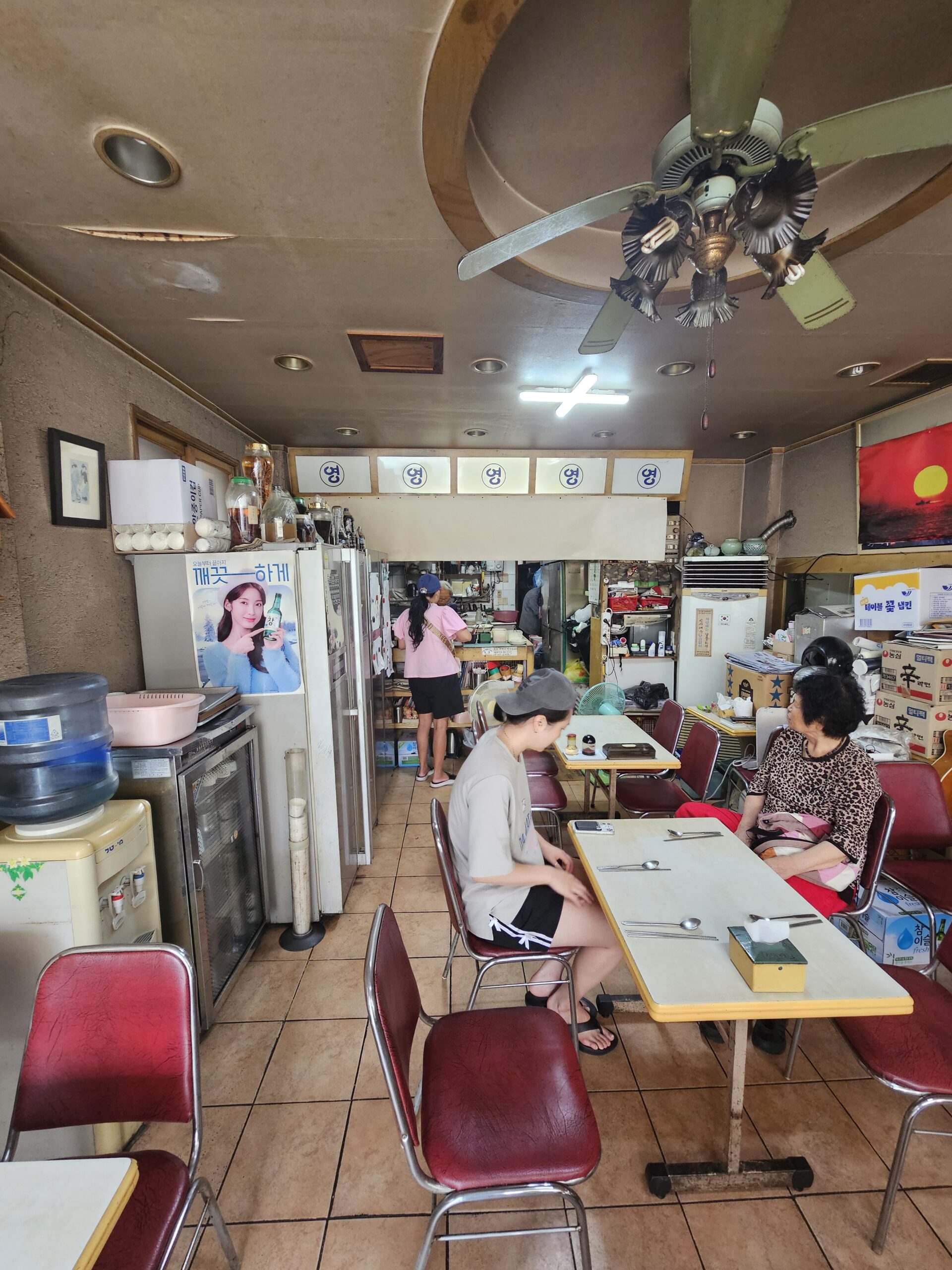 Closely spaced tables, ceiling fan, and kitchen at Yeongudong