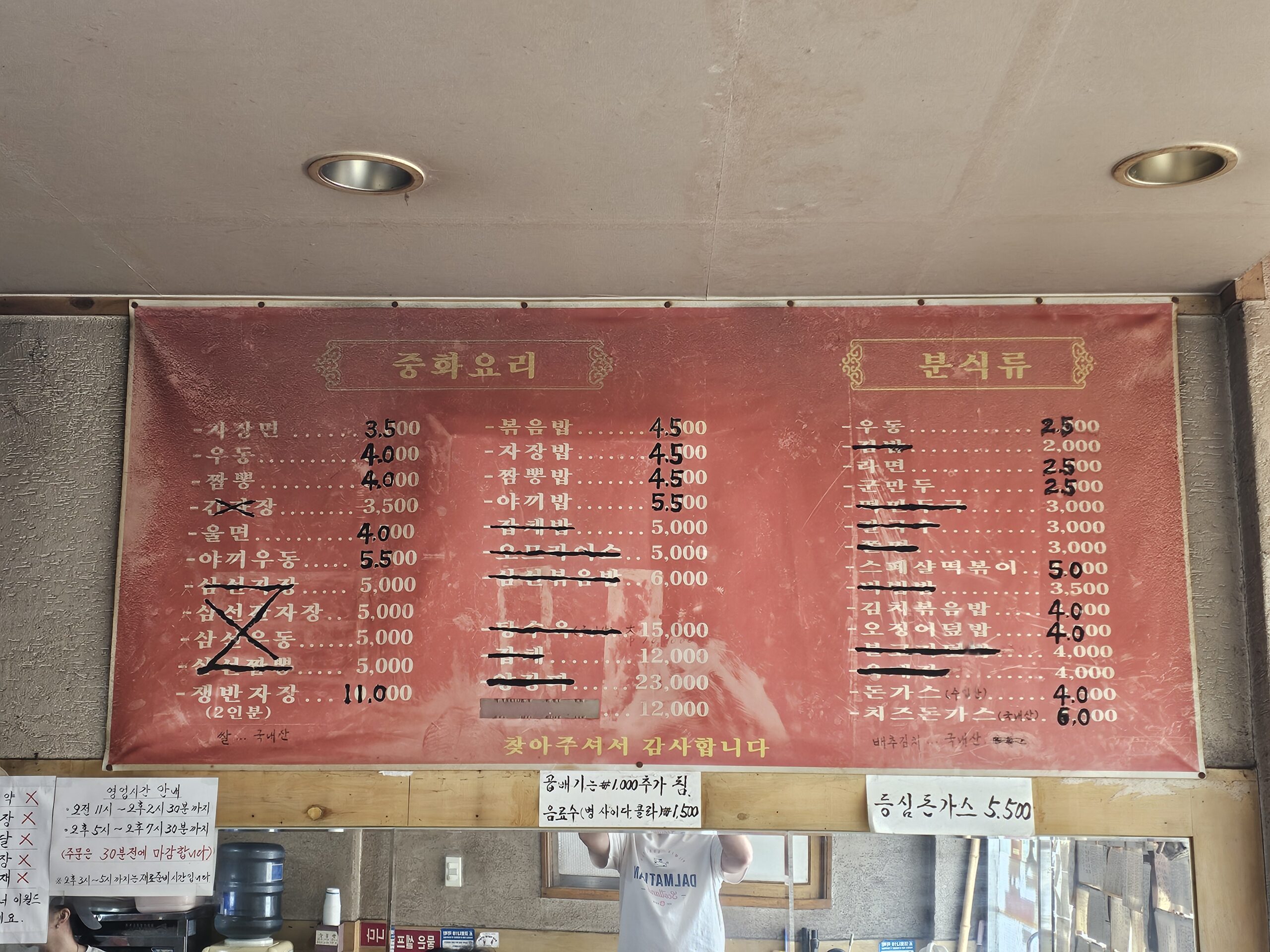 Menu board with handwritten prices over earlier prices