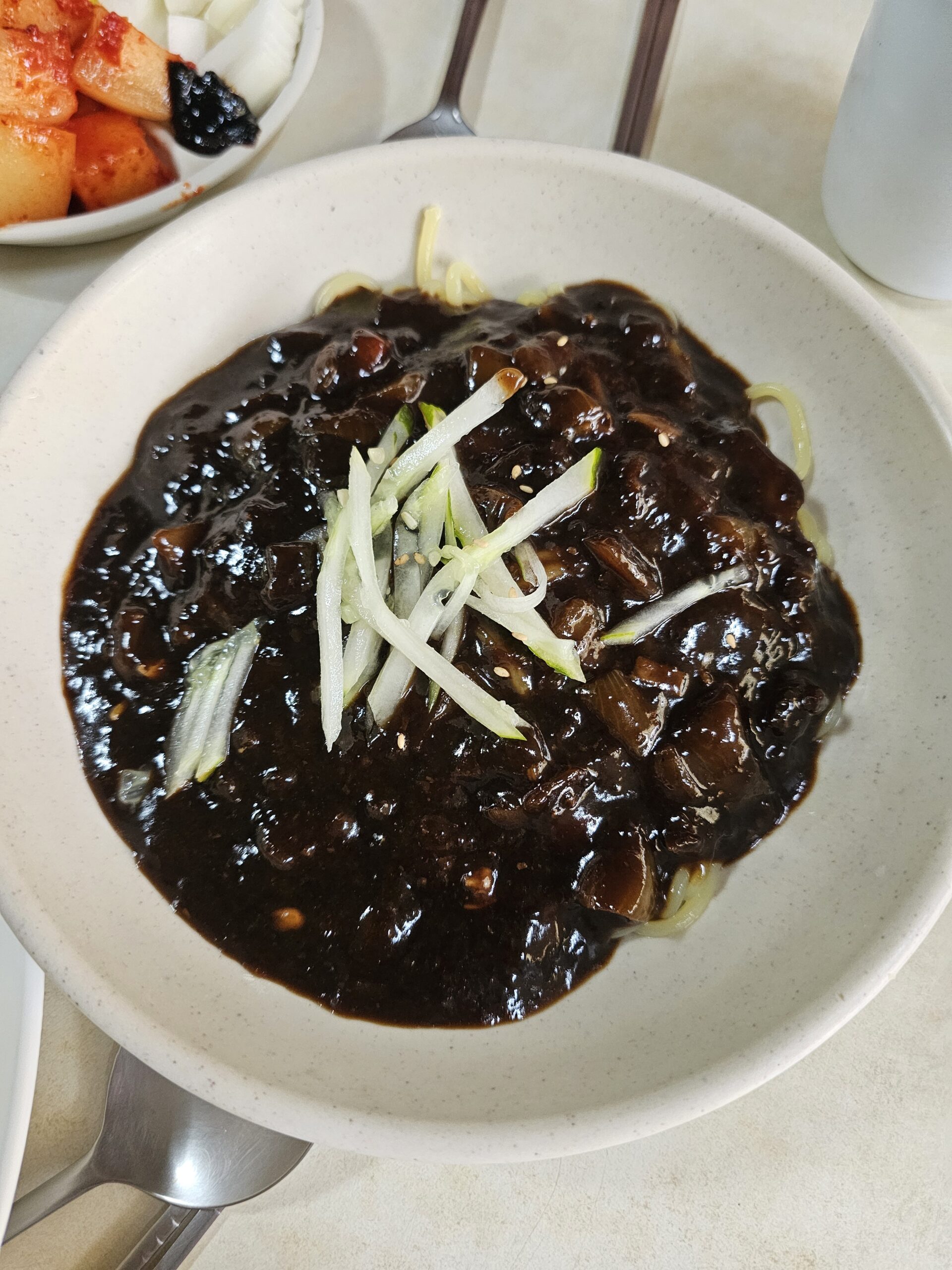 Jajangmyeon topped with sauce, large onion pieces, and sesame seeds